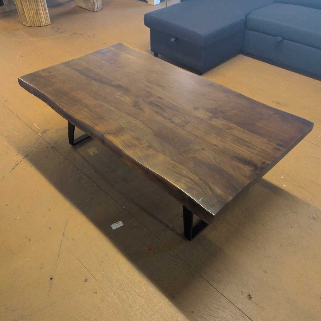 Wooden coffee table in a room with a blue sofa and wooden floor.