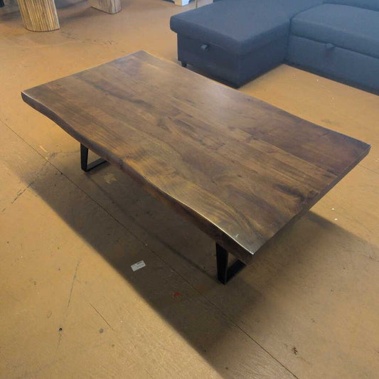 Wooden coffee table in a room with a blue sofa and wooden floor.