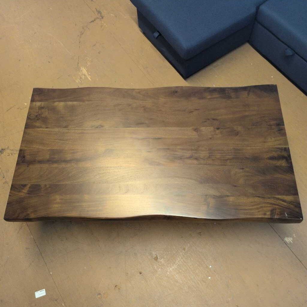 Wooden coffee table on a beige floor with blue upholstered furniture in the background