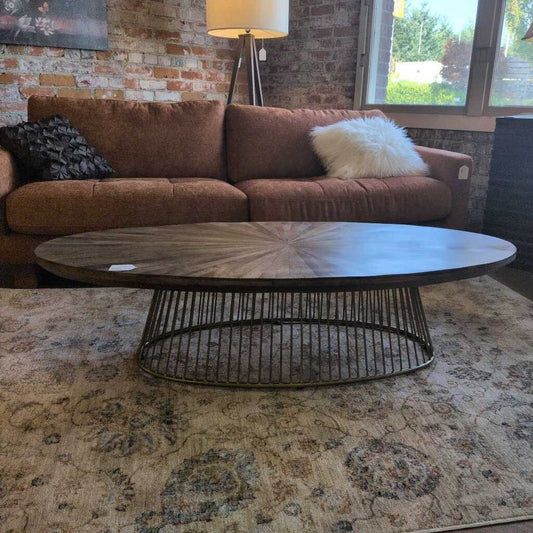 Brown sofa with decorative pillows and a round wooden coffee table in a living room setting.