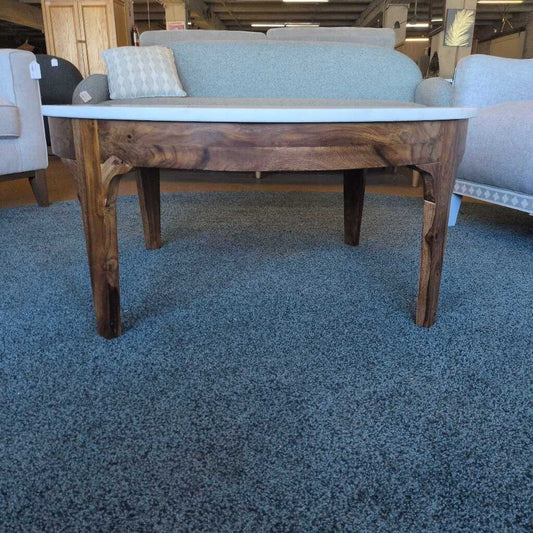 Wooden coffee table with a white top in a room with furniture and carpet.