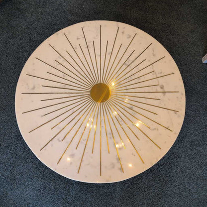 Round marble table with gold辐射 design on a dark floor