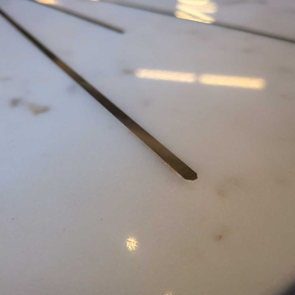 Close-up of a thin metal rod on a white surface with reflections