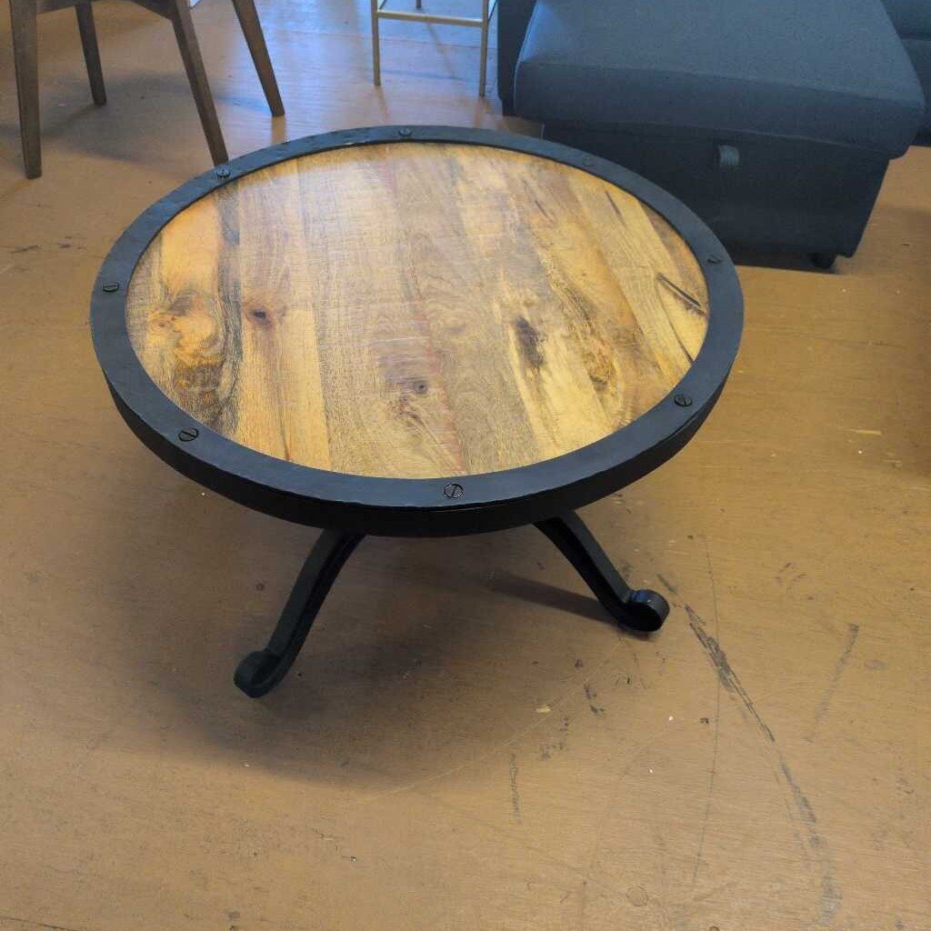 Round wooden table with metal legs on a wooden floor