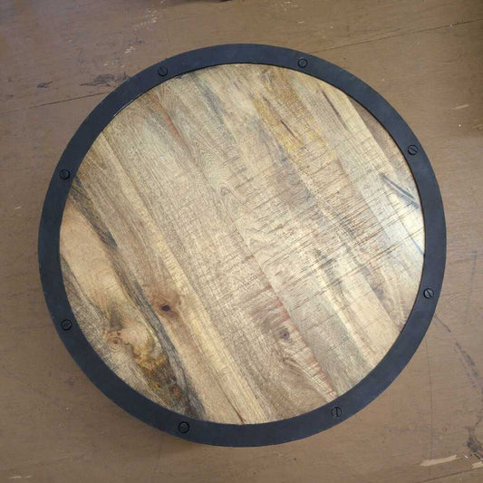 Round wooden surface with a black metal frame on a wooden floor.