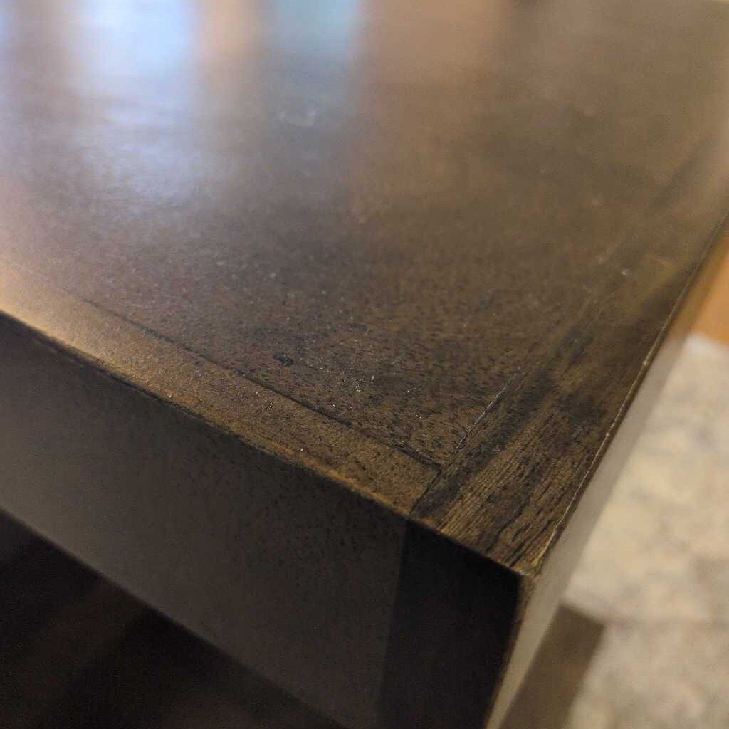 Close-up of a dark wooden surface with visible grain and texture.