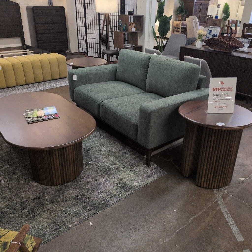 Modern living room setup with a green sofa, wooden coffee table, and side table.