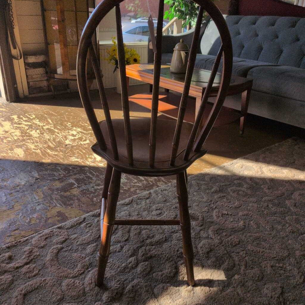 Wooden chair in a room with a couch and table in the background