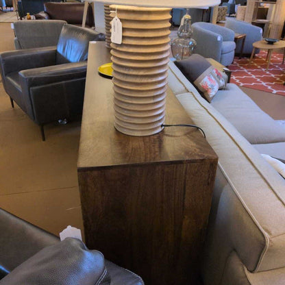Decorative lamp on a wooden table in a room with furniture and decor.