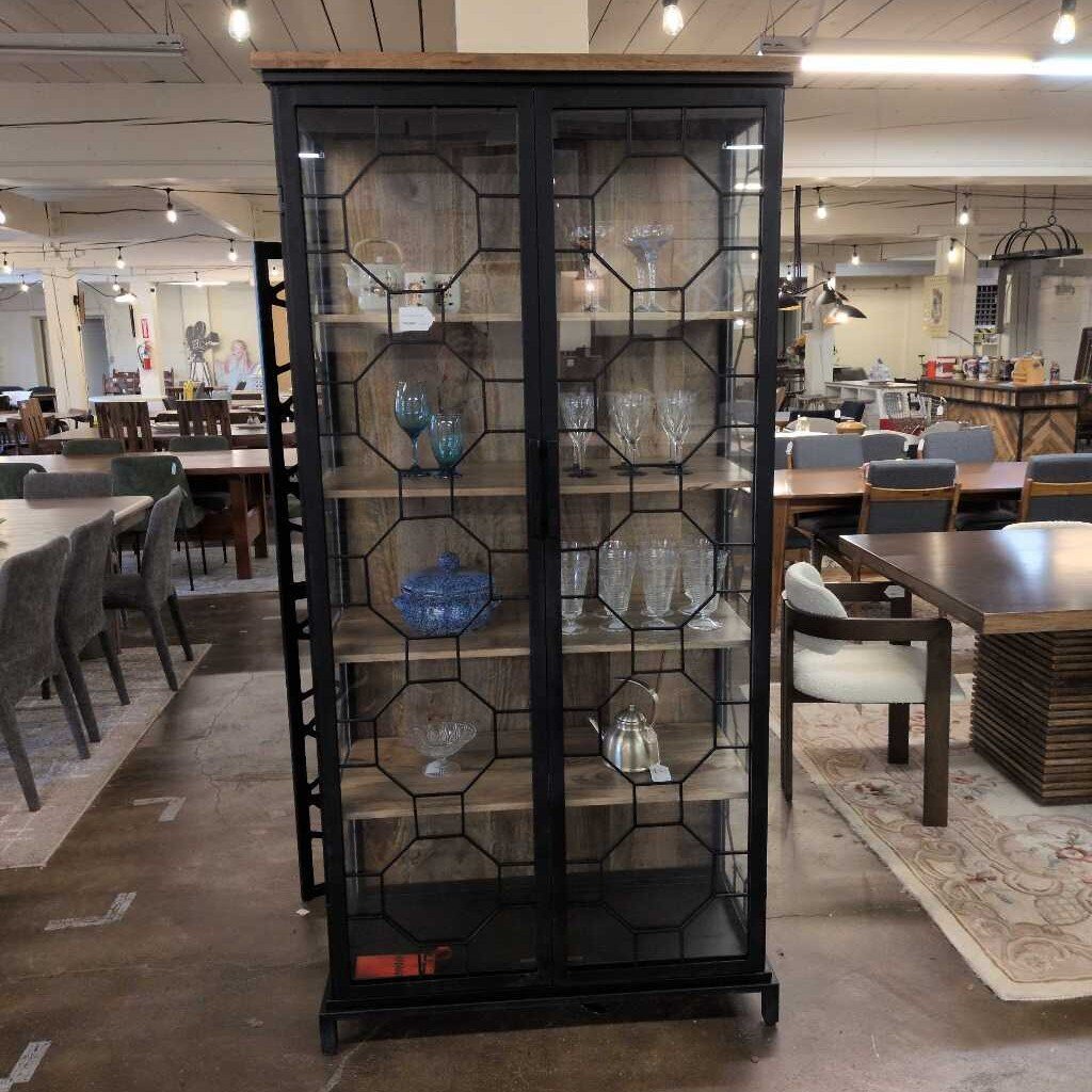 Black glass-fronted display cabinet in a showroom with tables and chairs.