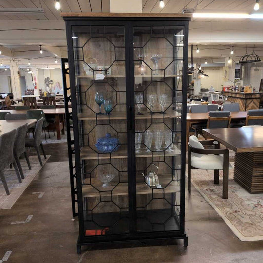 Black glass-fronted display cabinet in a showroom with tables and chairs.