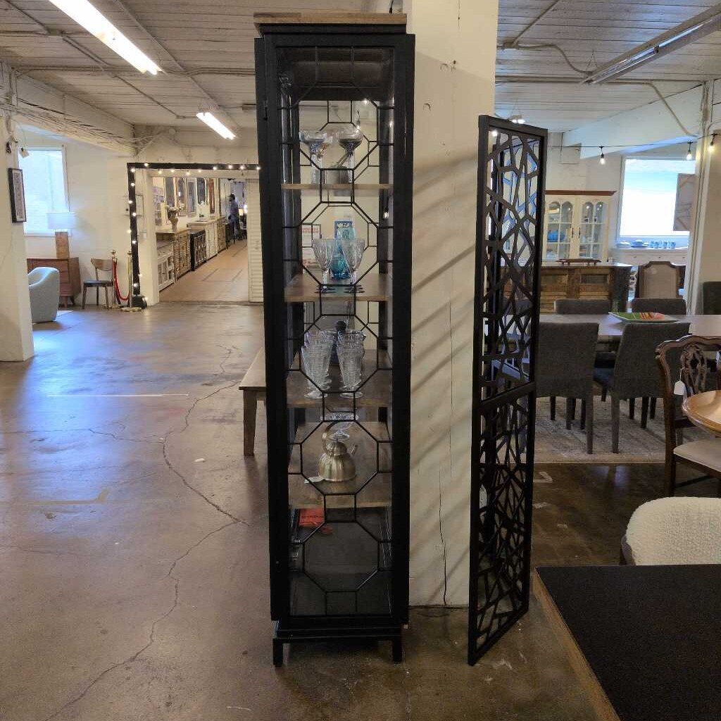Tall black decorative shelf with glass panels in a showroom setting