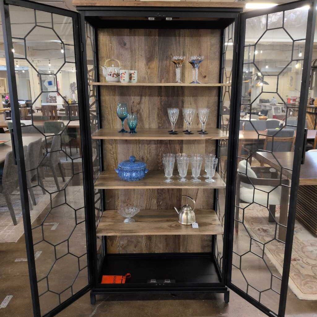 Wooden cabinet with glass doors displaying various items in a room setting.