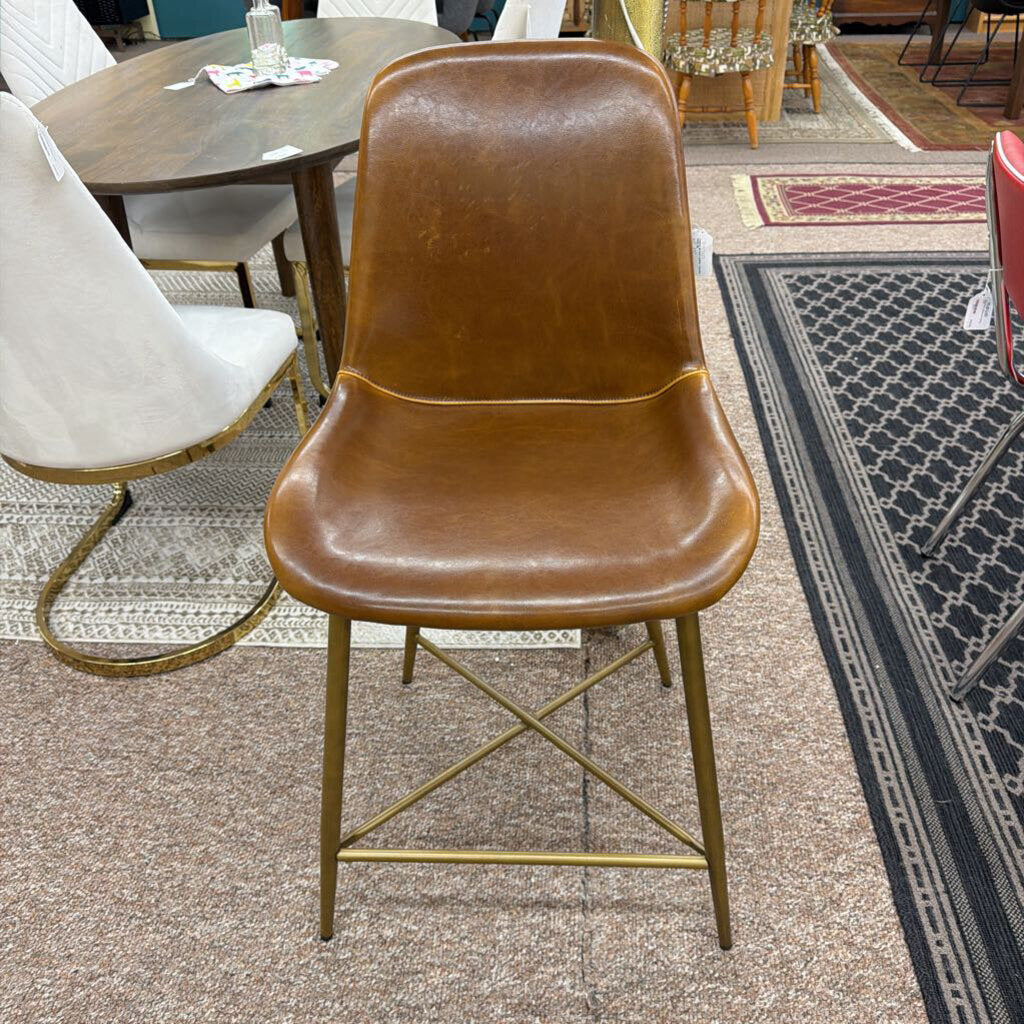 Brown leather chair with gold metal legs on a carpeted floor.