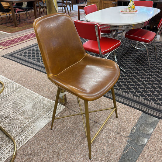 Brown chair with gold legs on a patterned floor