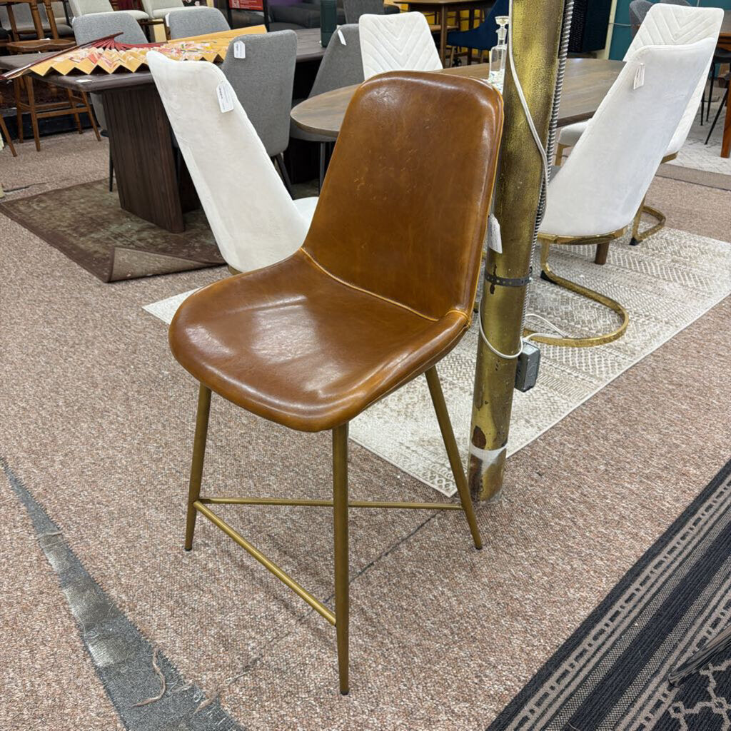 Brown chair with gold legs on a textured floor