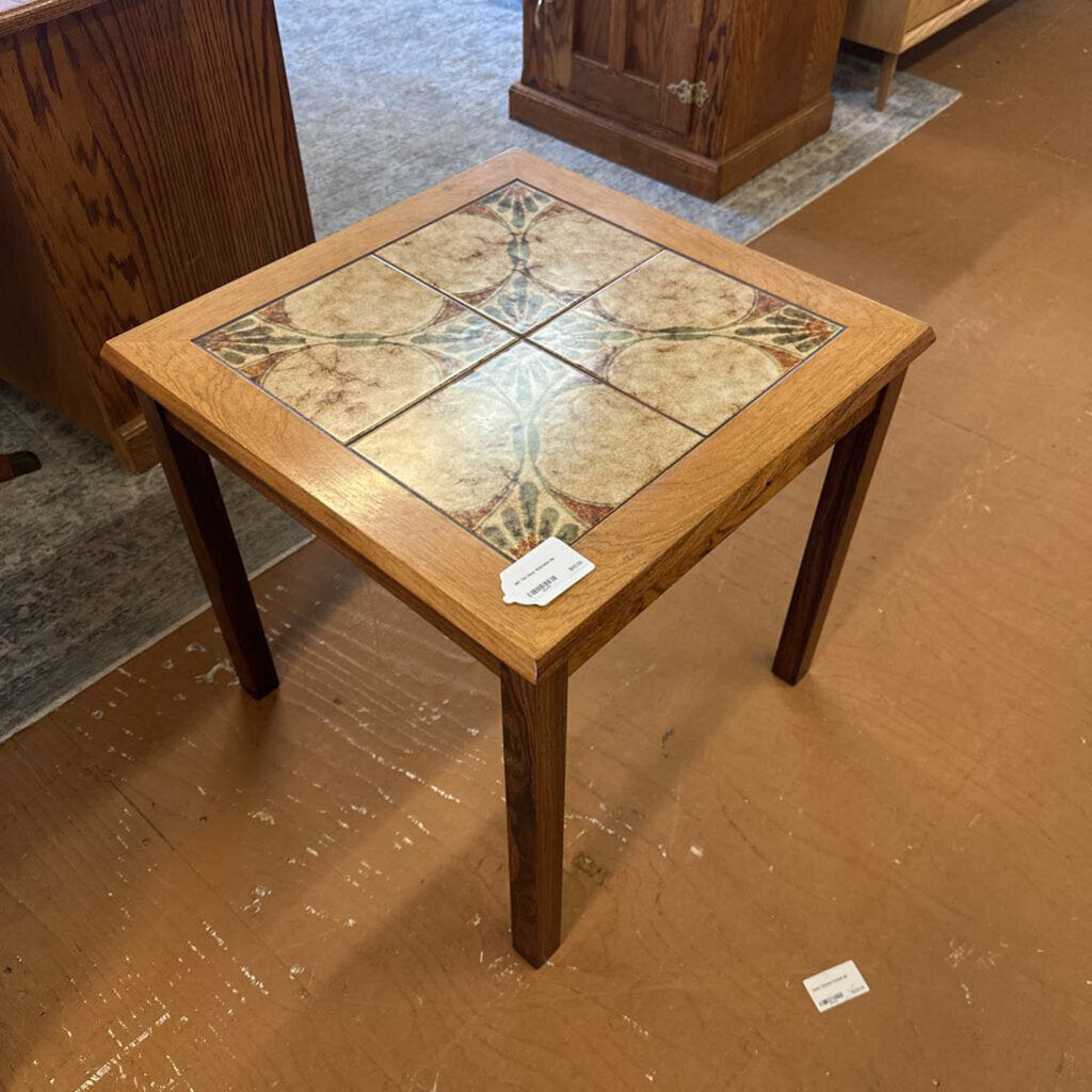 Small wooden table with a tiled top on a brown floor.