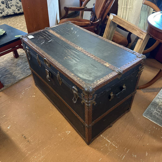 Vintage trunk on a wooden floor with chairs in the background