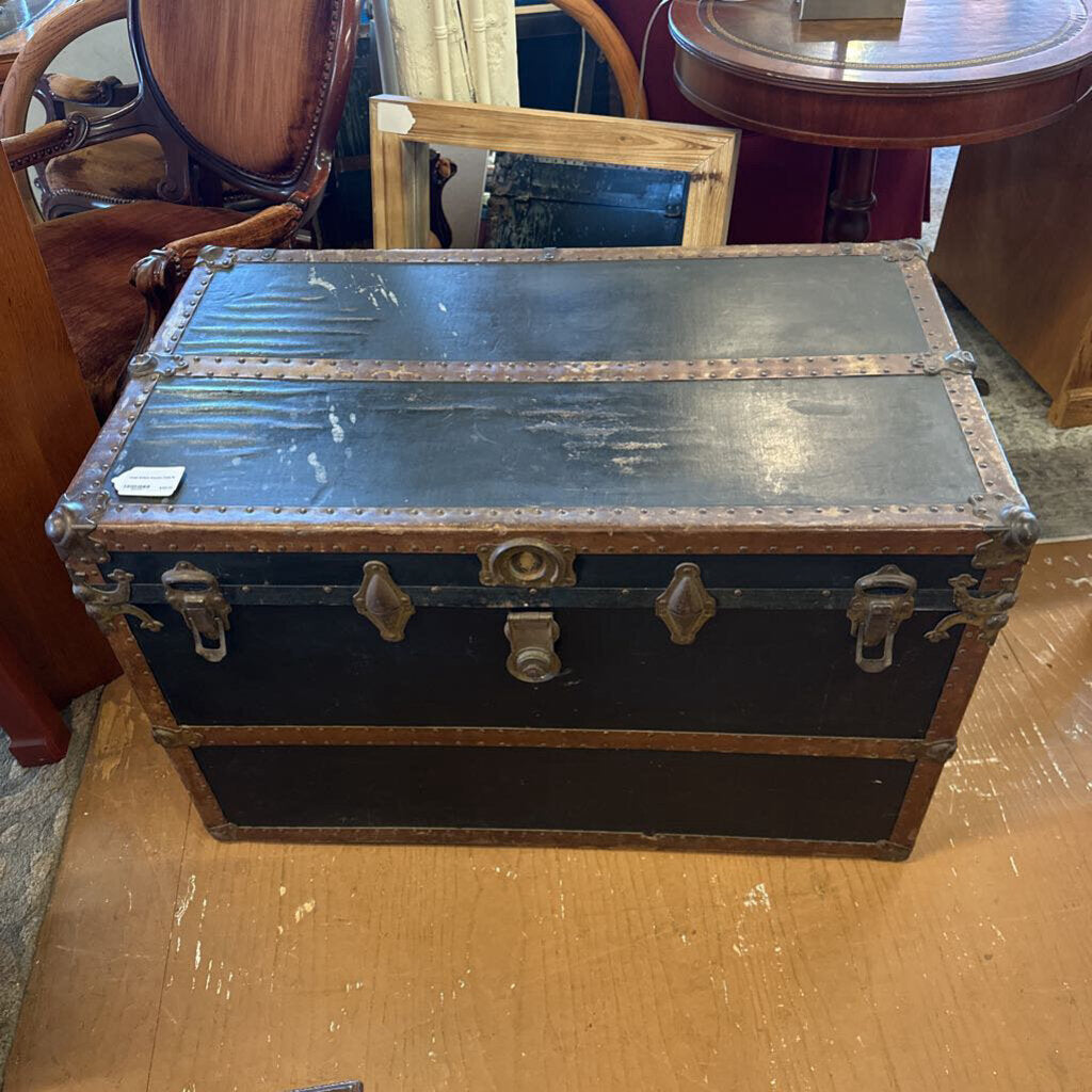 Vintage-style black trunk with metal clasps on a wooden surface