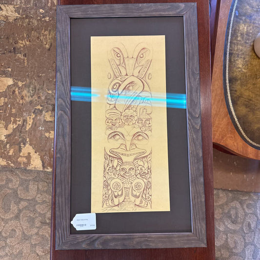 Framed artwork with a tiki design on a textured surface