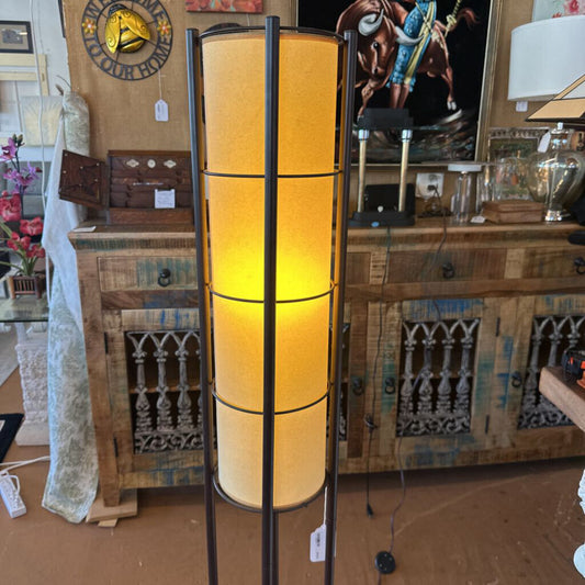 Floor lamp with cylindrical yellow shades in a room with wooden furniture and decor.