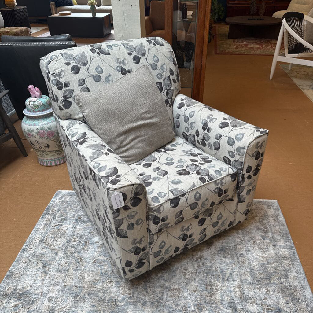 Patterned armchair with a gray pillow on a marble surface in a room setting.