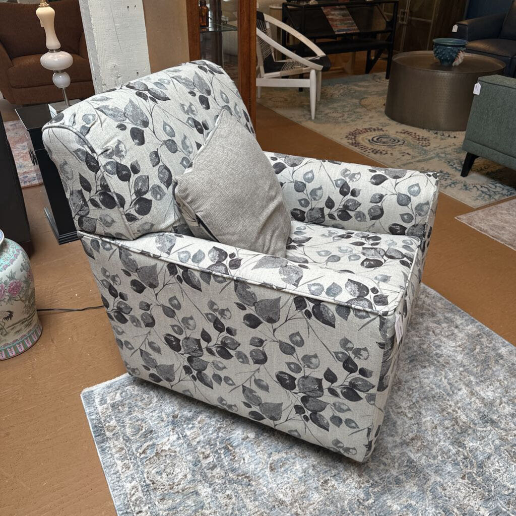 Floral-patterned armchair with a gray pillow on a marble floor.