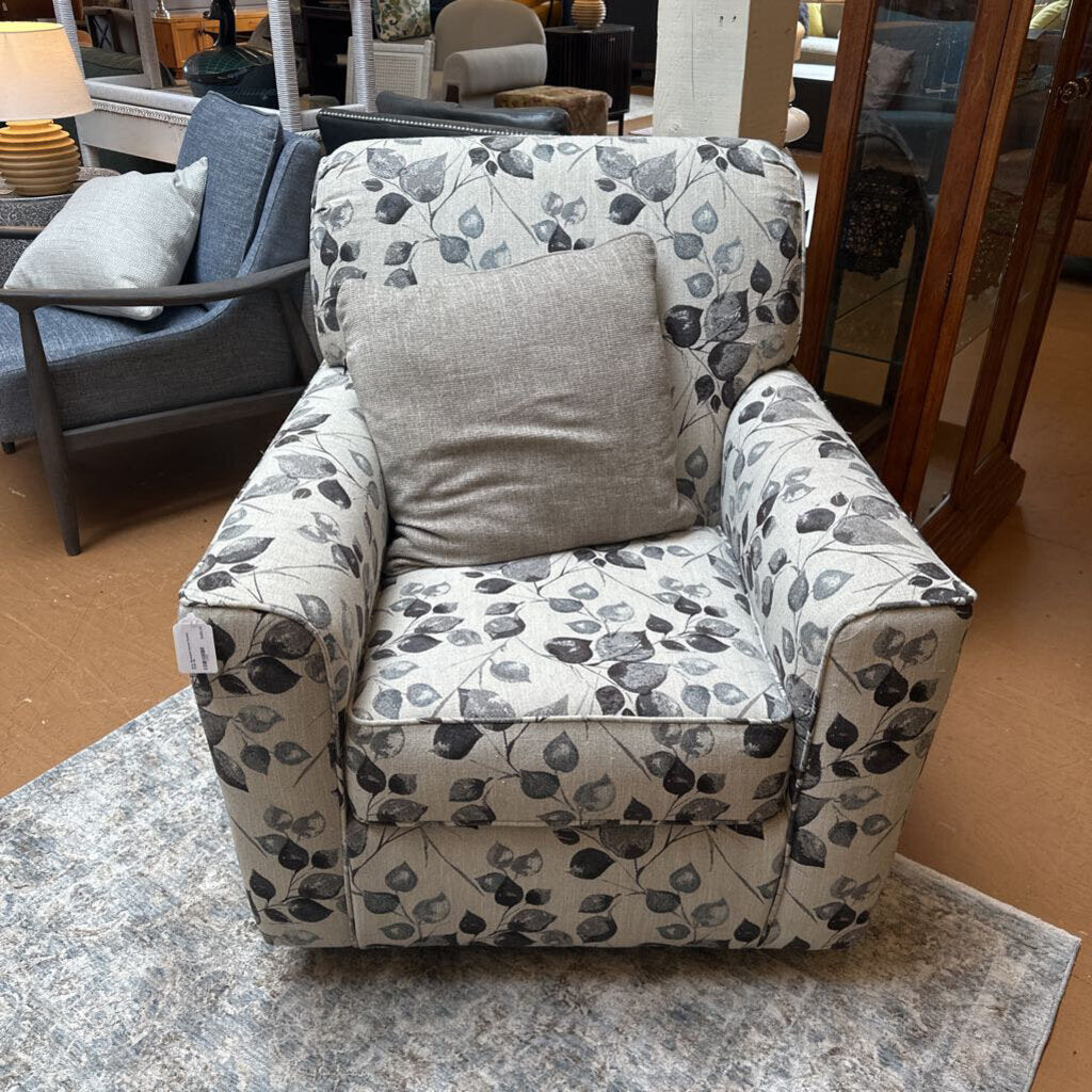 Floral-patterned armchair with a gray pillow in a furniture store setting
