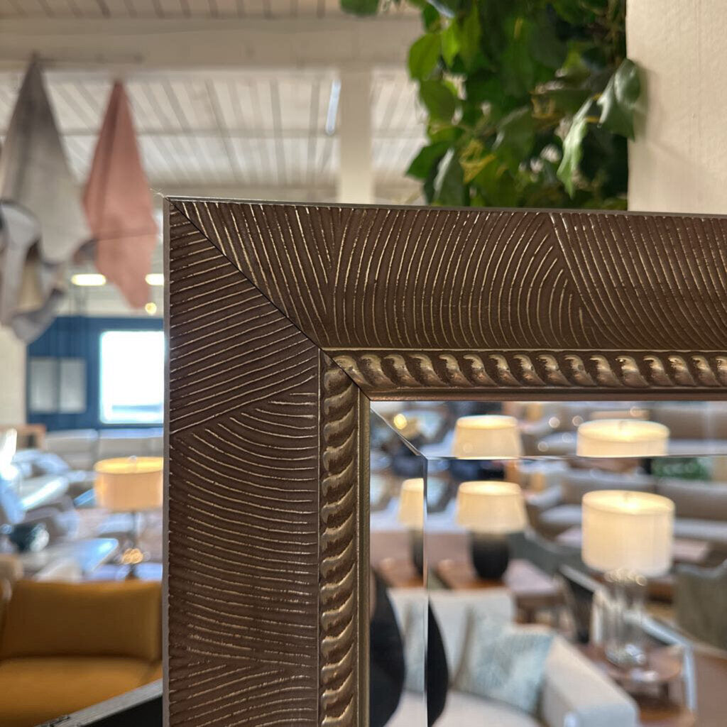 Decorative mirror with textured frame in a room setting