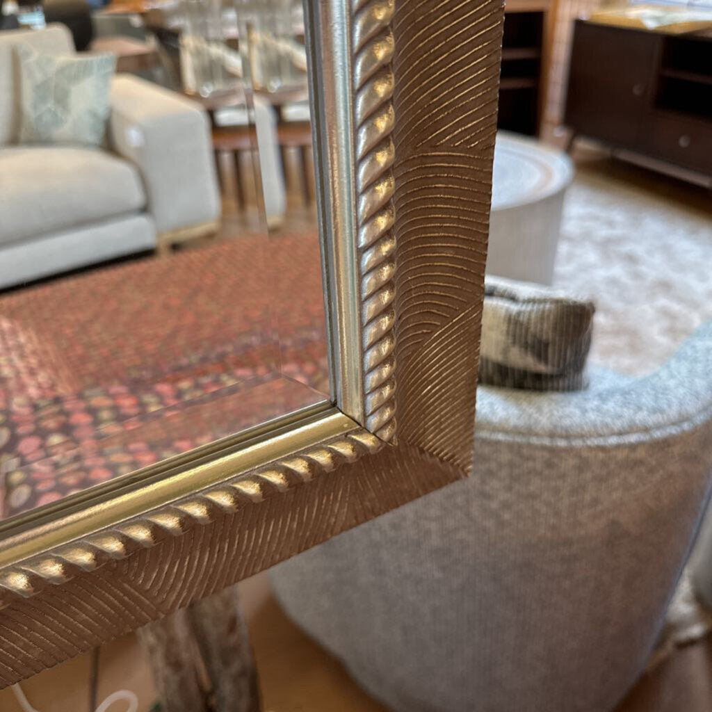Gold-framed mirror in a room with furniture and decor