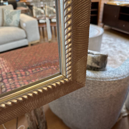 Gold-framed mirror in a room with furniture and decor