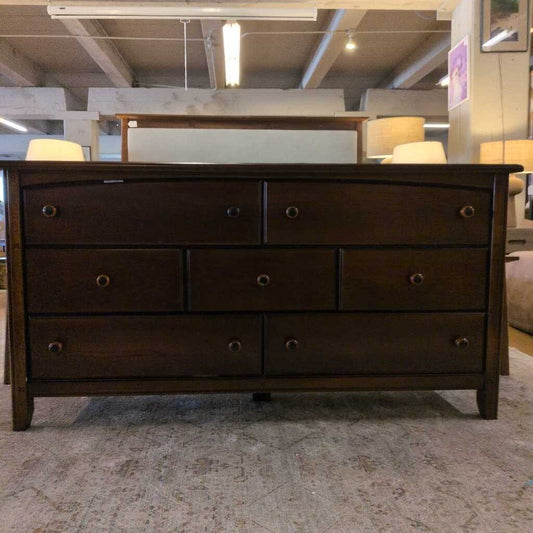 Dark wood dresser with multiple drawers in a room setting