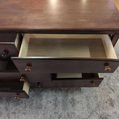 Wooden dresser with open drawer on a textured surface