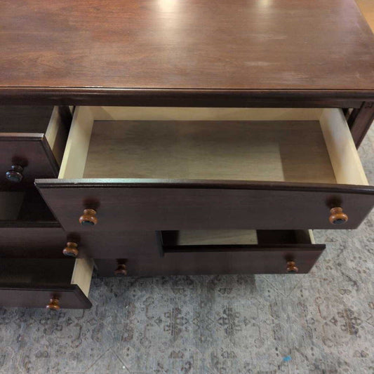 Wooden dresser with open drawer on a textured surface