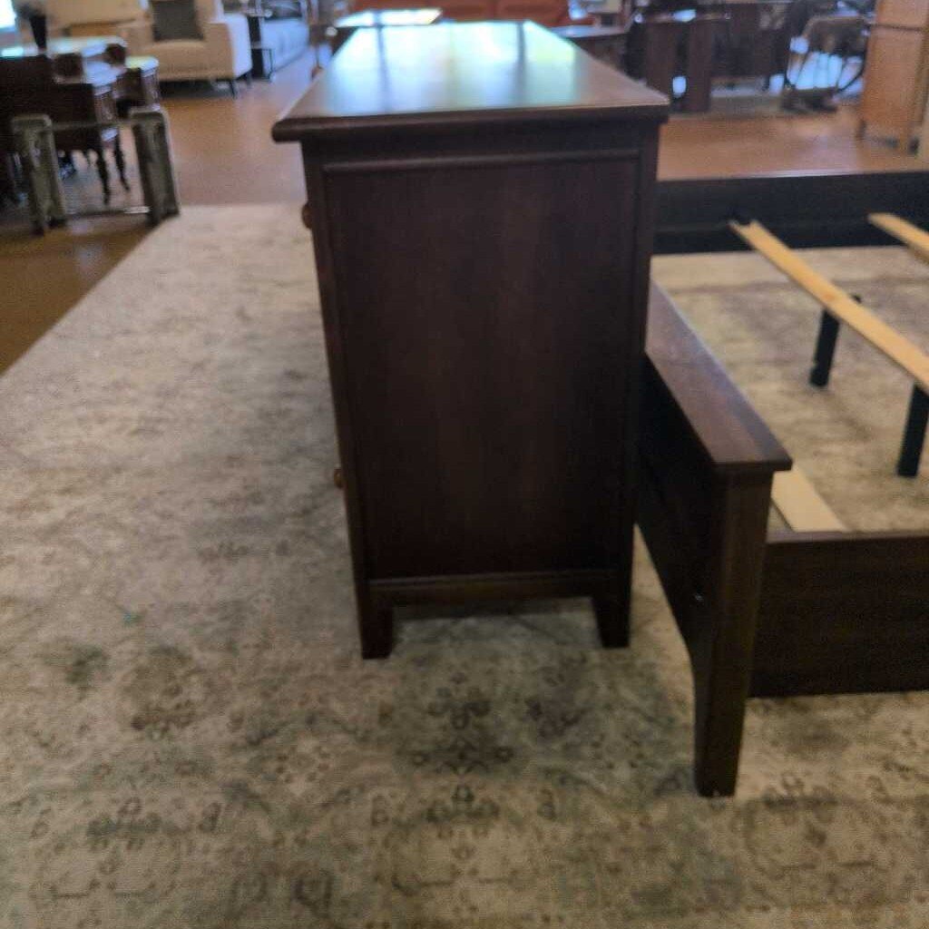 Dark wooden desk in a room with carpeted floor and furniture.