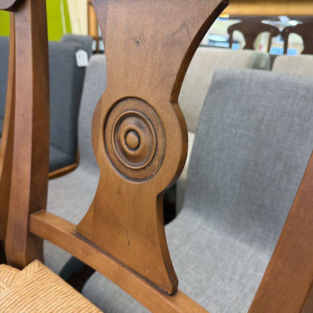 Close-up of a wooden chair with intricate carvings in an indoor setting.