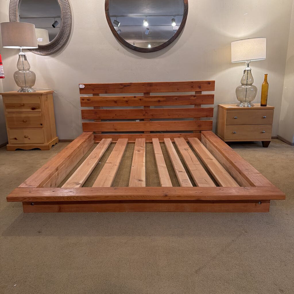 Wooden bed frame in a room with nightstands and lamps.