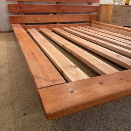 Wooden bed frame on a carpeted floor
