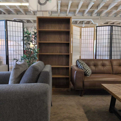 Living room with gray sofa, brown leather couch, wooden bookshelf, and decorative pillows.