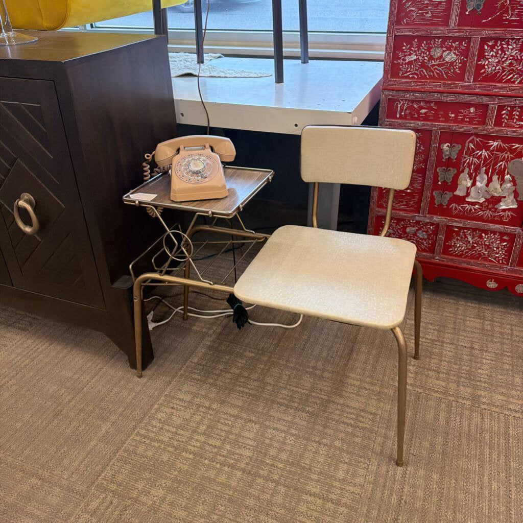 Beige chair in a room with a vintage phone on a small table and a red patterned wall.
