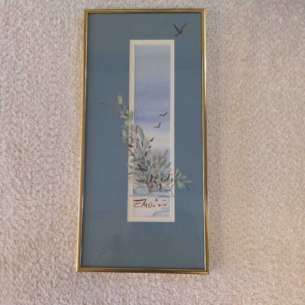 Framed artwork with a nature scene on a textured wall