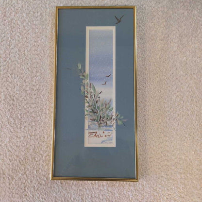 Framed artwork with a nature scene on a textured wall