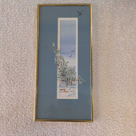 Framed artwork with a nature scene on a textured wall