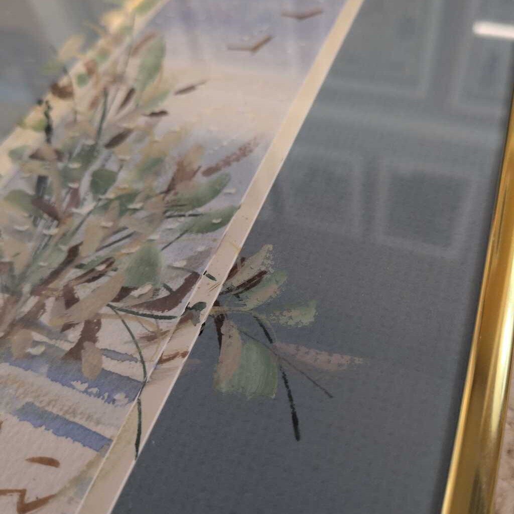 Close-up of a floral painting with a gold frame on a textured wall.