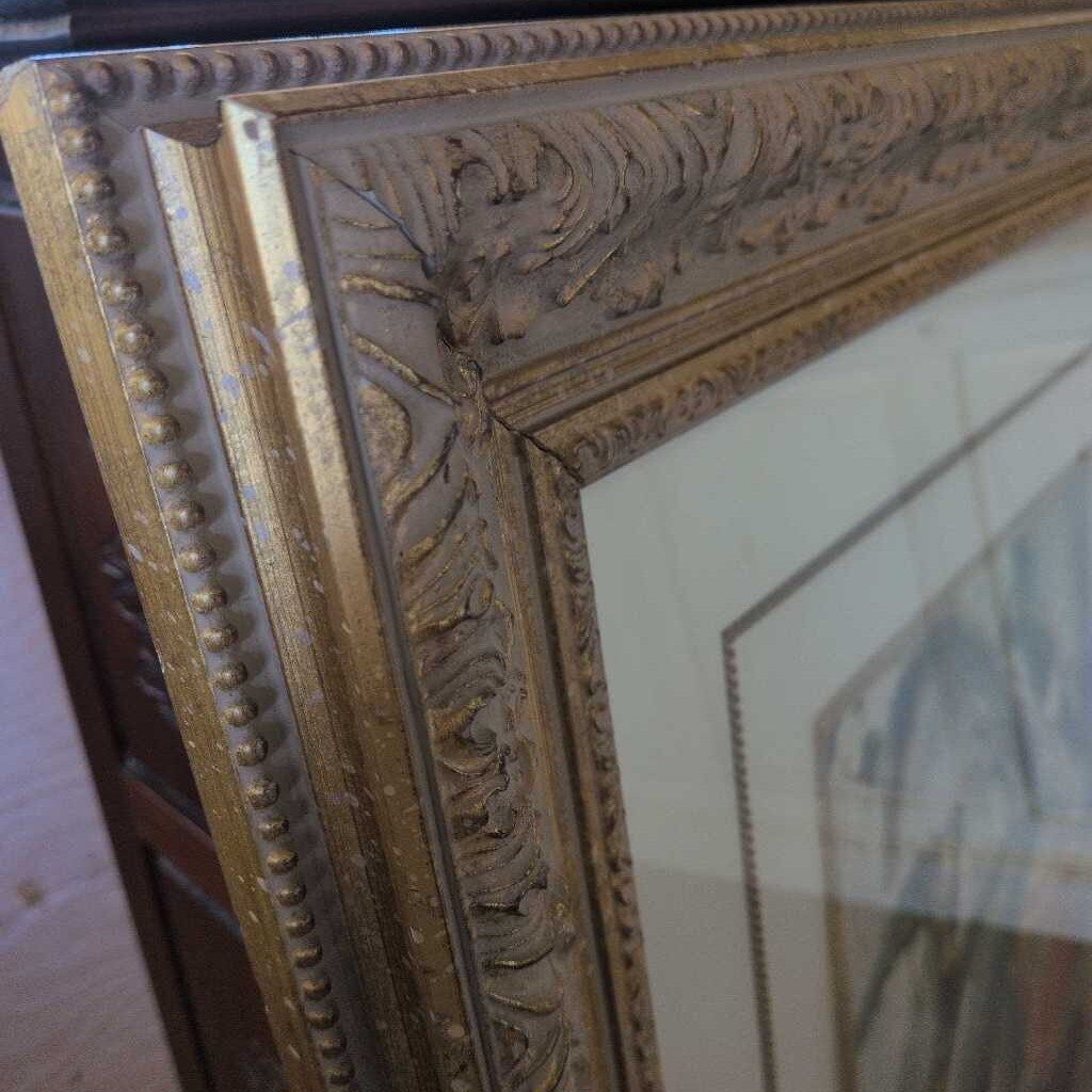 Close-up of an ornate gold mirror frame with intricate detailing.