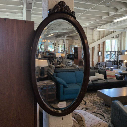 Decorative oval mirror reflecting a living room with furniture and decor.