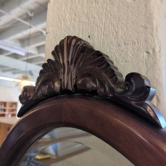 Close-up of an ornate wooden mirror frame with detailed carvings.