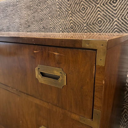 Wooden cabinet with brass handle against a patterned wall