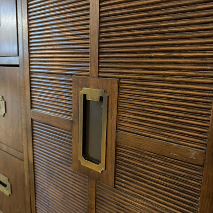 Close-up of a wooden door with a textured pattern and a rectangular gold handle.