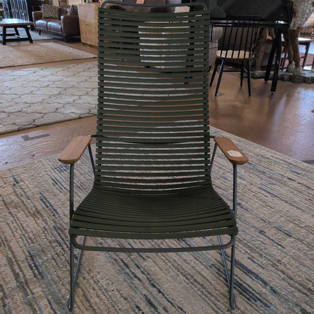 Green lounge chair on a patterned rug in a room with furniture and people in the background